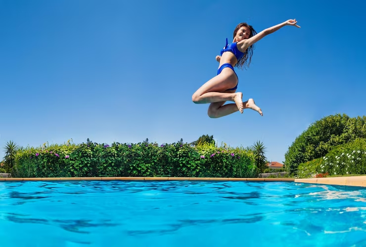 Vrouw springt in zwembad tijdens zonvakantie bij luxe resort