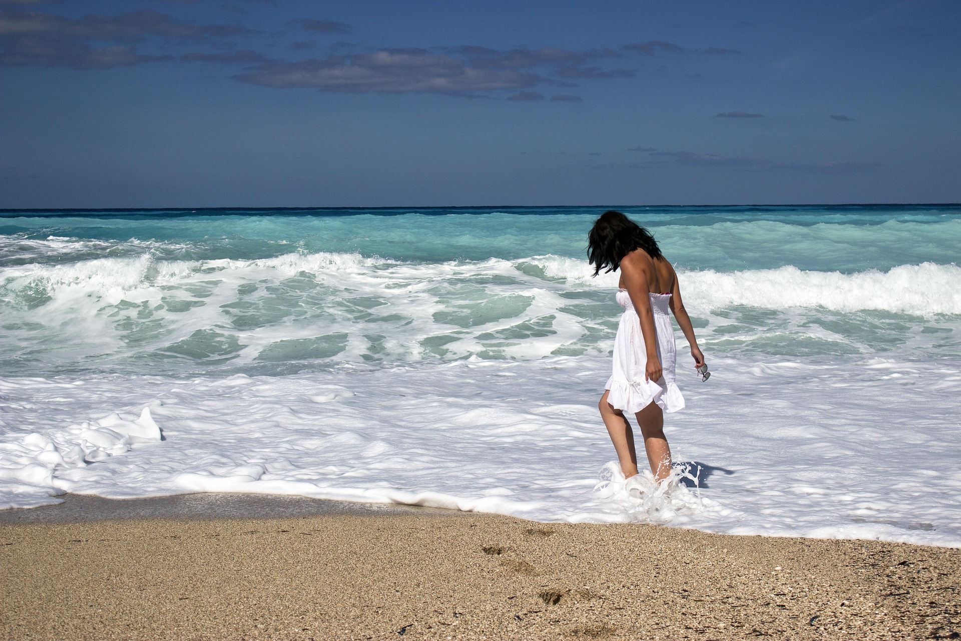 Vrouw op het strand met haar voeten in zee